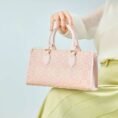 song-brocade-leather-handbag-pink-gold-dingsheng-motif-model-sitting-knee-handheld